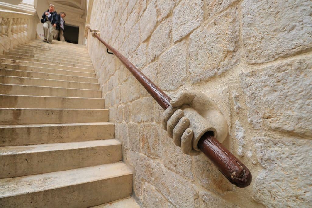 Staircase railing with a sculpture of a hand holding it