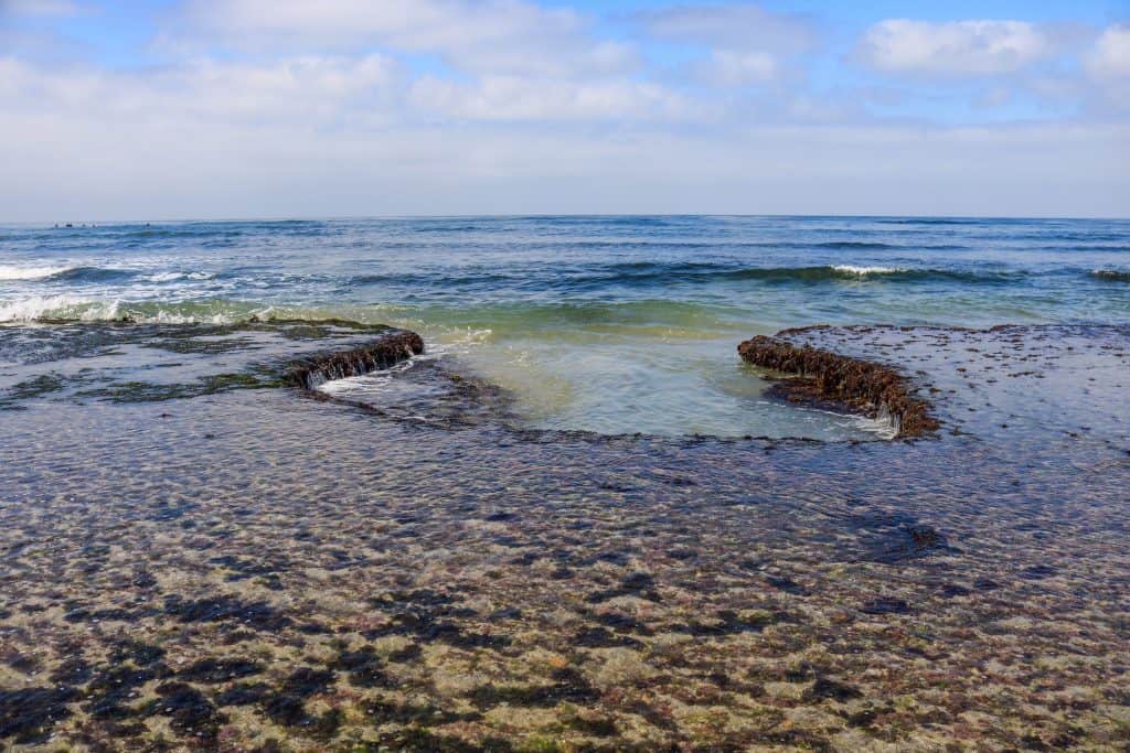 The rock formations create both big and small pools along the shore