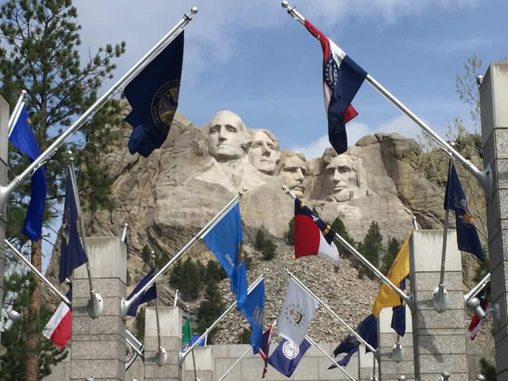 Front entrance to Mount Rushmore with a row of flags and the president faces beyond is one of the best things to do in South Dakota.