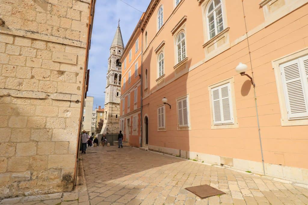 A charming church tower viewed between two buildings of an alleyway in old town Zadar.