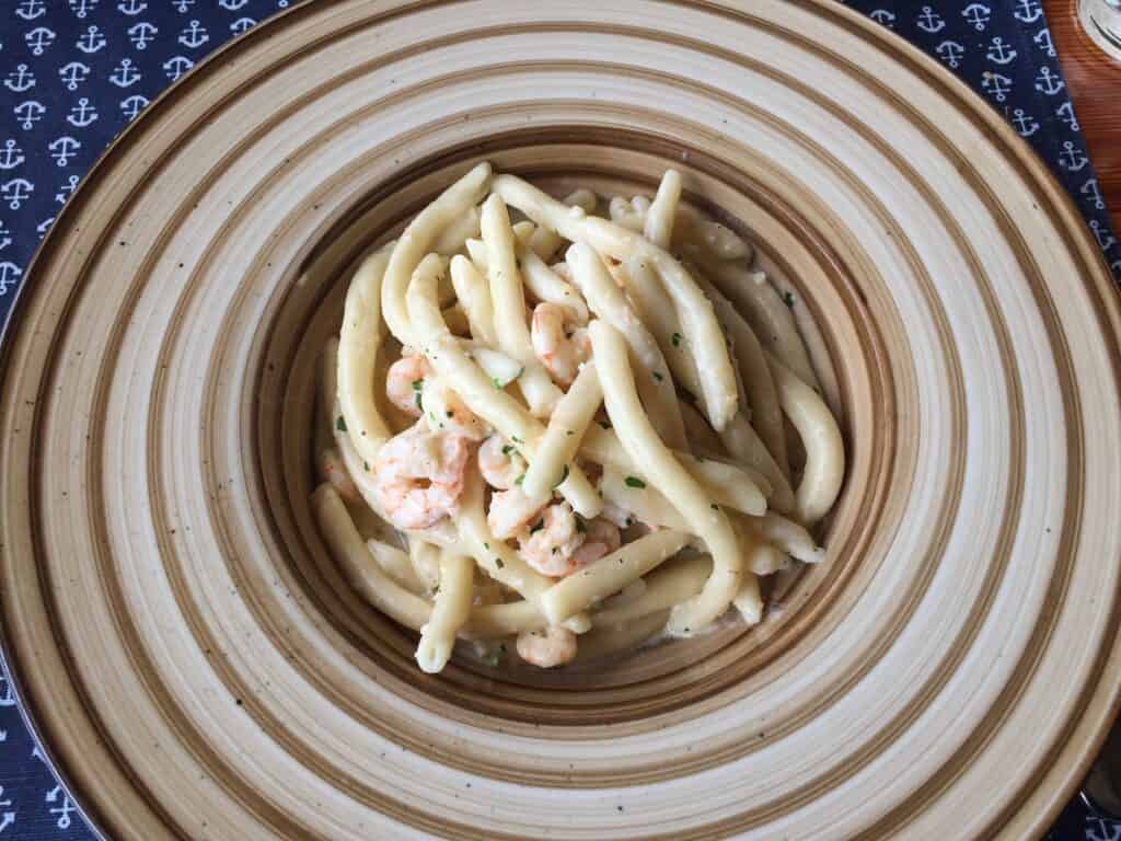 A plate with a mound of pasta with a white sauce and shrimp in Split, Croatia.