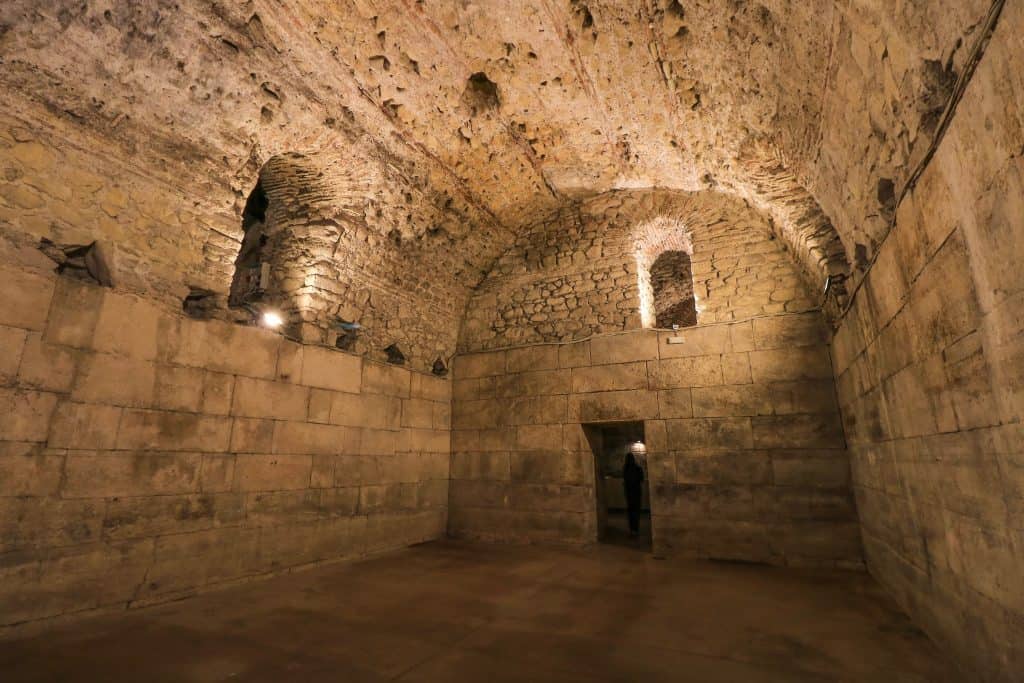 Ruins of the Cellar, a large room made of stone with low lighting and an arched ceiling that is beautiful.