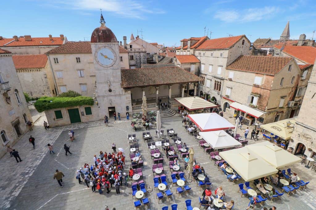 View of the town square, clock tower, and outdoor cafes from the first level of the St. Lawrence Cathedral bell tower in Trogir old town.