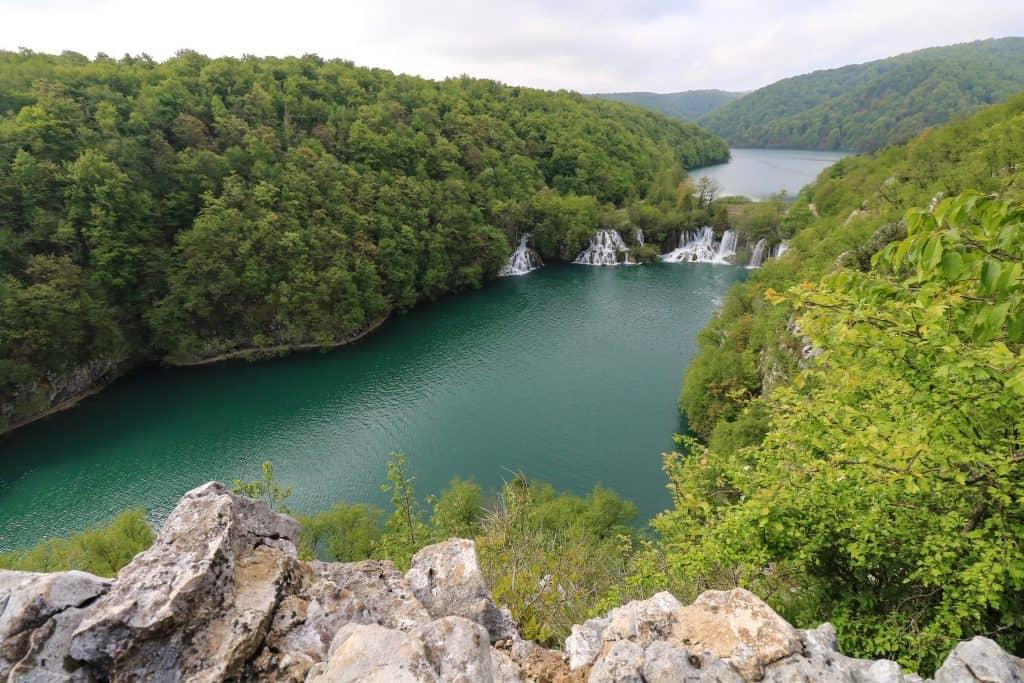 View from standing on top of a cliff looking down at the lakes and waterfalls in the distance at Plitvice Lower Lakes in Croatia.
