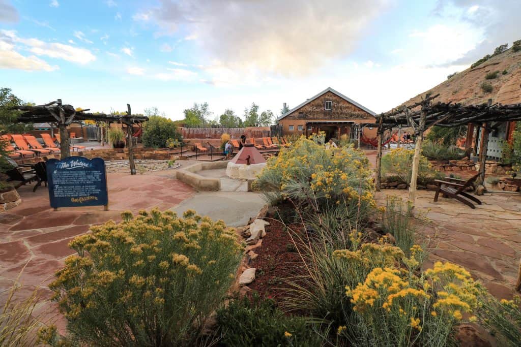 A broad look of the different mineral pools, natural foliage, and lounge chairs outside at the Ojo Caliente. 