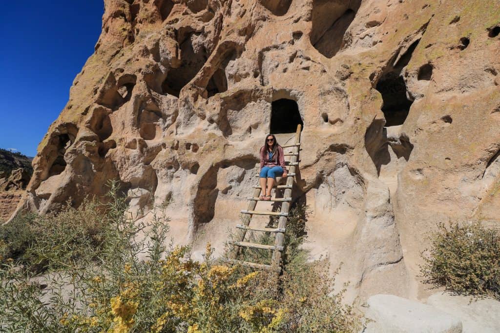 Sitting at the top of one of the ladders you can climb up to one of the dwellings carved into the rocks at Bandelier National Monument.