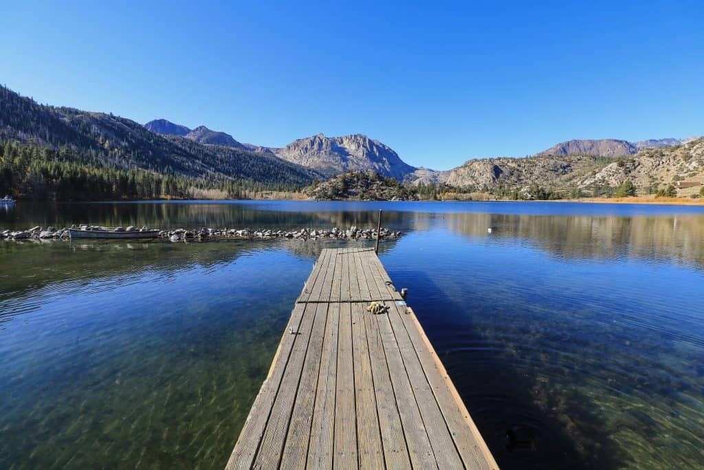 Sitting on the dock at Gull Lake looking out at a crystal clear blue water and mountains in the distance, one of the lakes on the June Loop in Mammoth Lakes.