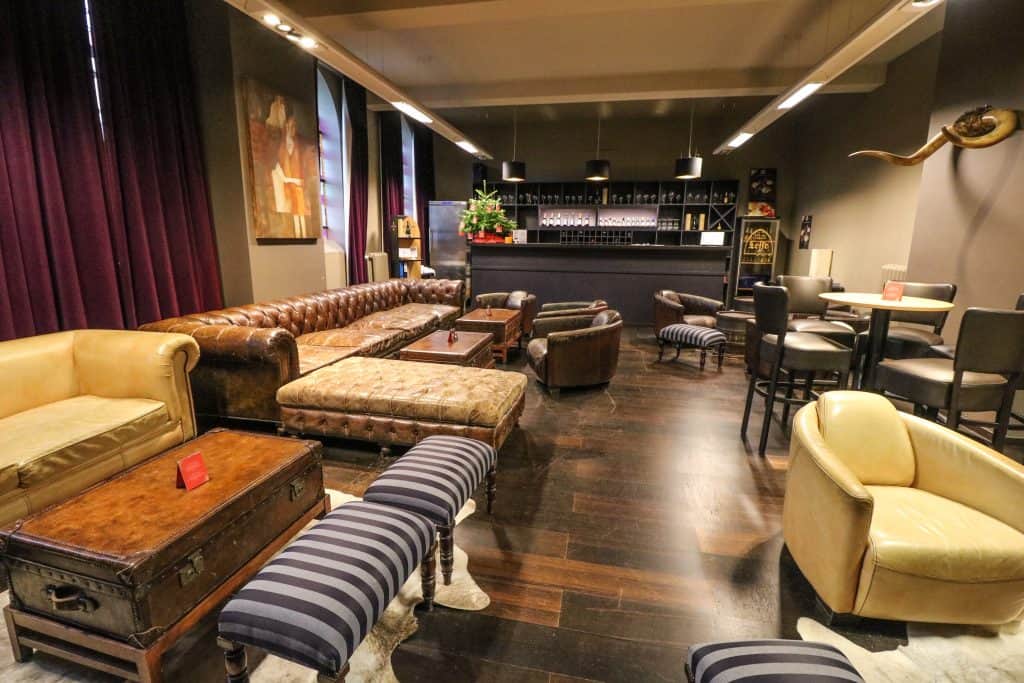 A large lounge in the Leffe Museum with a bar and several cozy couches and leather chairs next door to the museum in Dinant, Belgium.