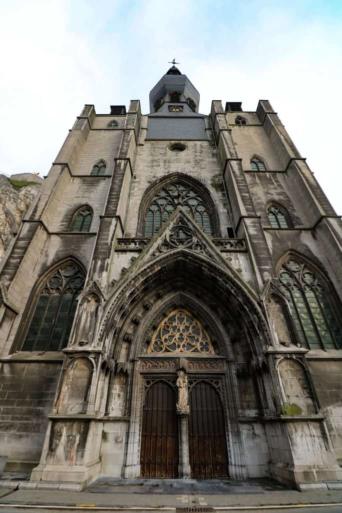 Standing looking up at the front facade of the gothic architecture of the cathedral in Dinant, Belgium with its skilled craftsmanship.