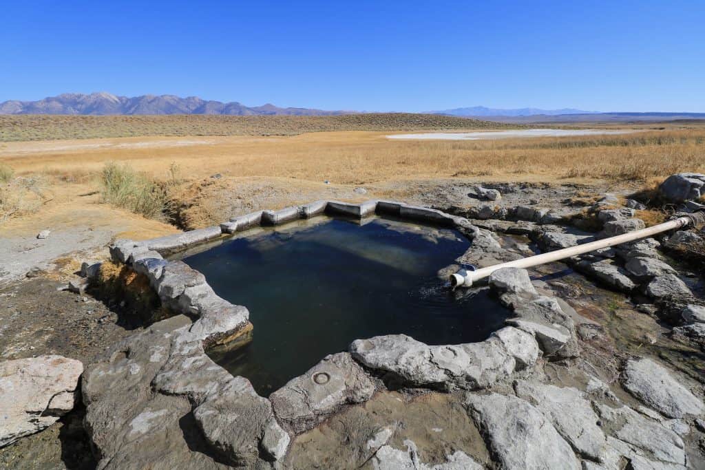 A close up of Shepherd's Hot Springs with a small pipe carrying hot water from the surrounding springs.