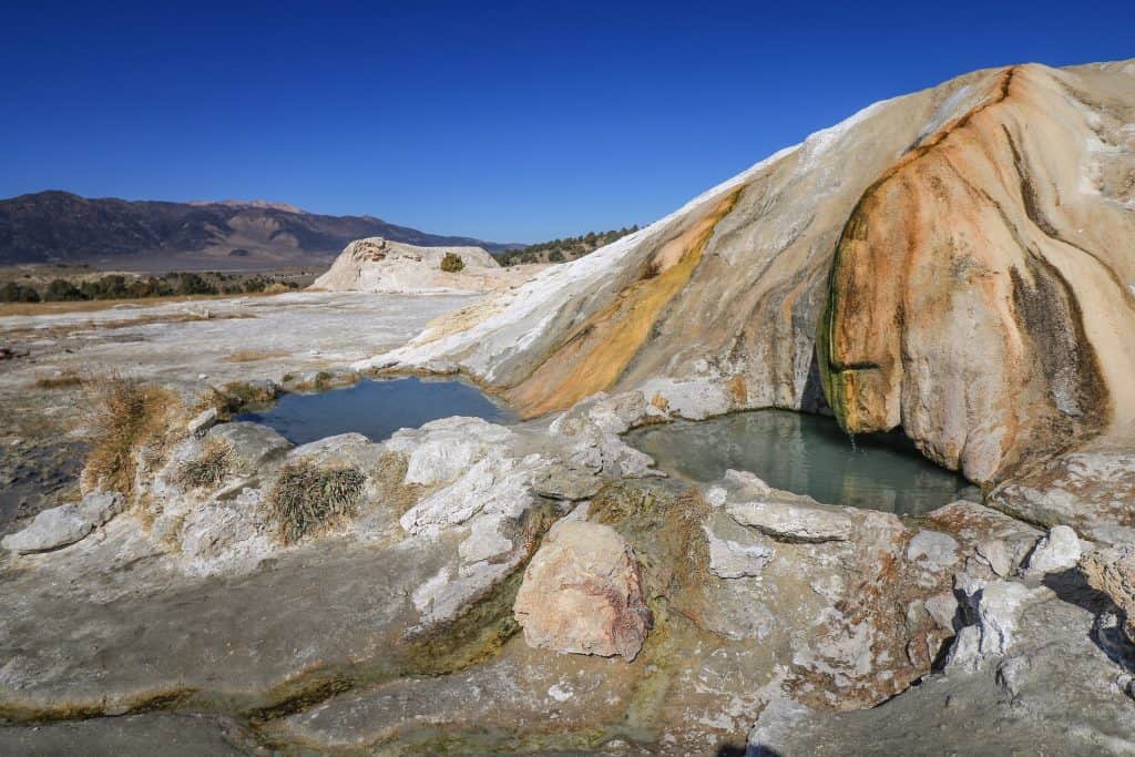 A close up of two of the natural hot springs pools with water that has a pretty blue-gray color at Travertine Hot Springs.