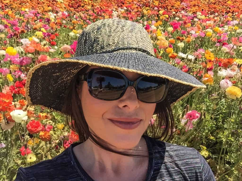 Me taking a selfie with rows of gorgeous Ranunculus flowers behind me in Carlsbad, CA.