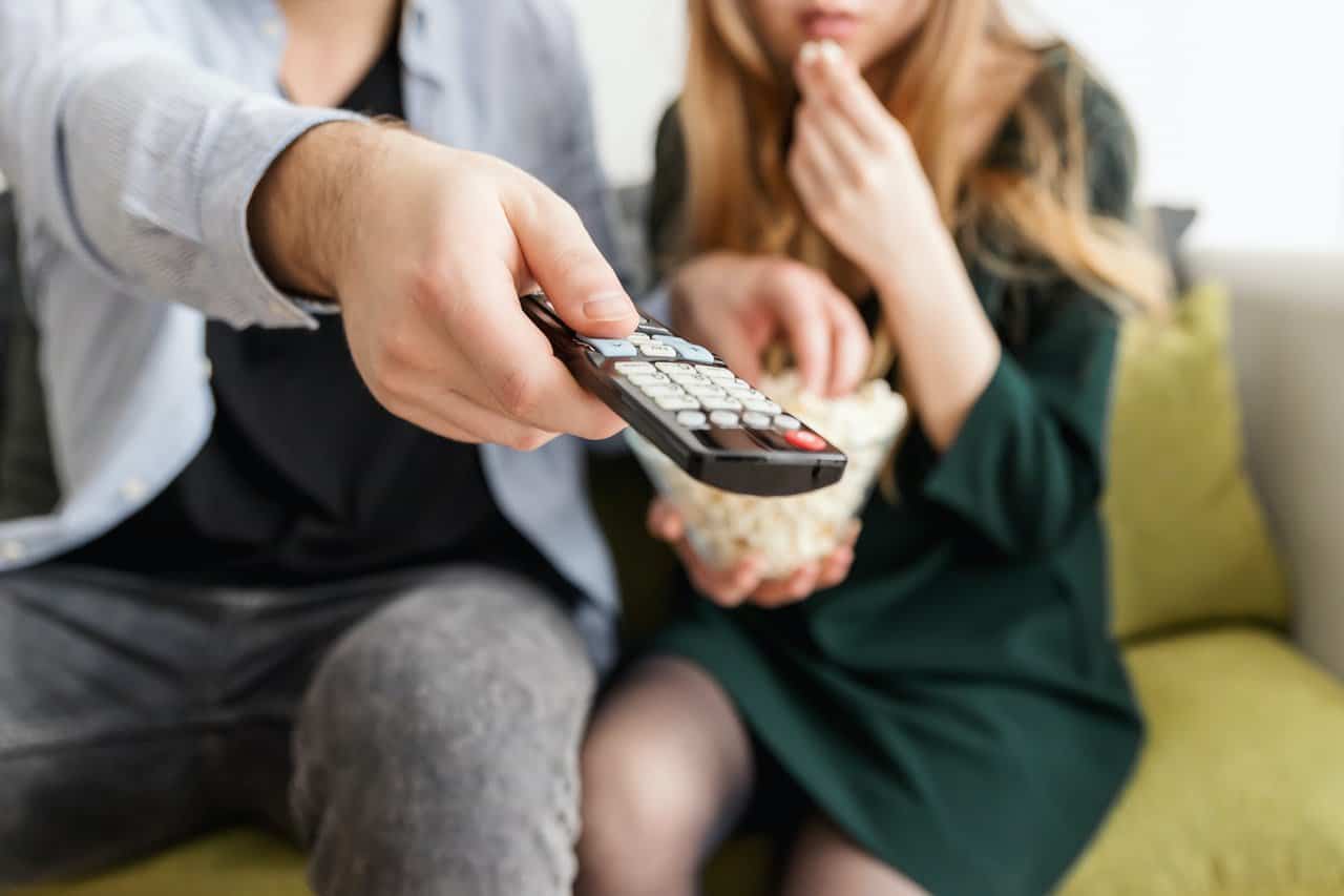 A man and woman with a remote control to watch TV