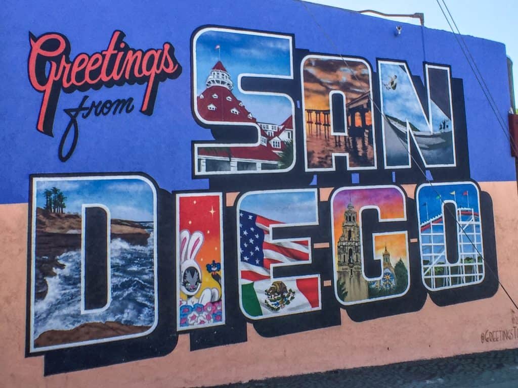 The guide to the best tacos in San Diego in front of the Greetings from San Diego sign 