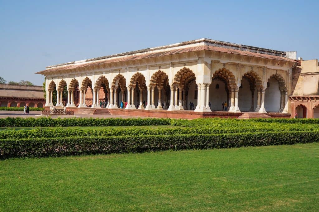 A beautiful long temple with a series of scalloped arches a in pale yellow against a red sandstone base