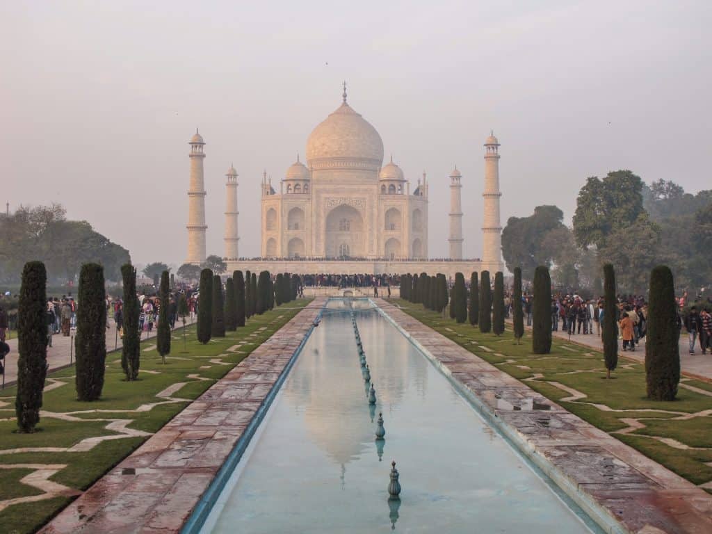 The Taj Mahal at the end of a long rectangular pool with an afternoon glow