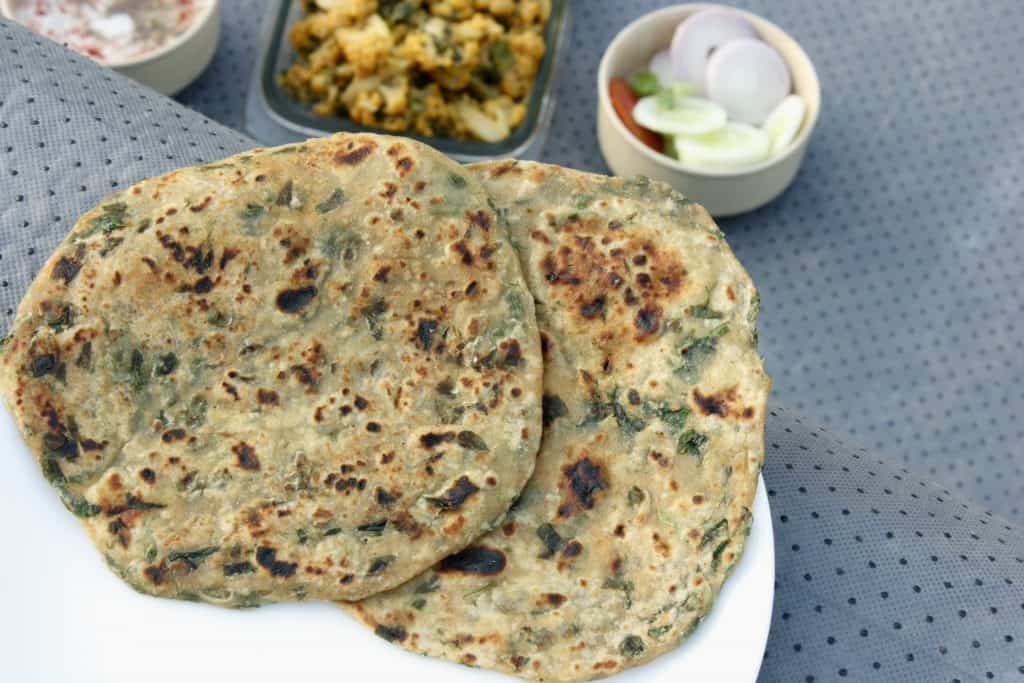 Two stuffed Paratha flatbread made with fenugreek leaves. Served with chilled yogurt and vegetables.