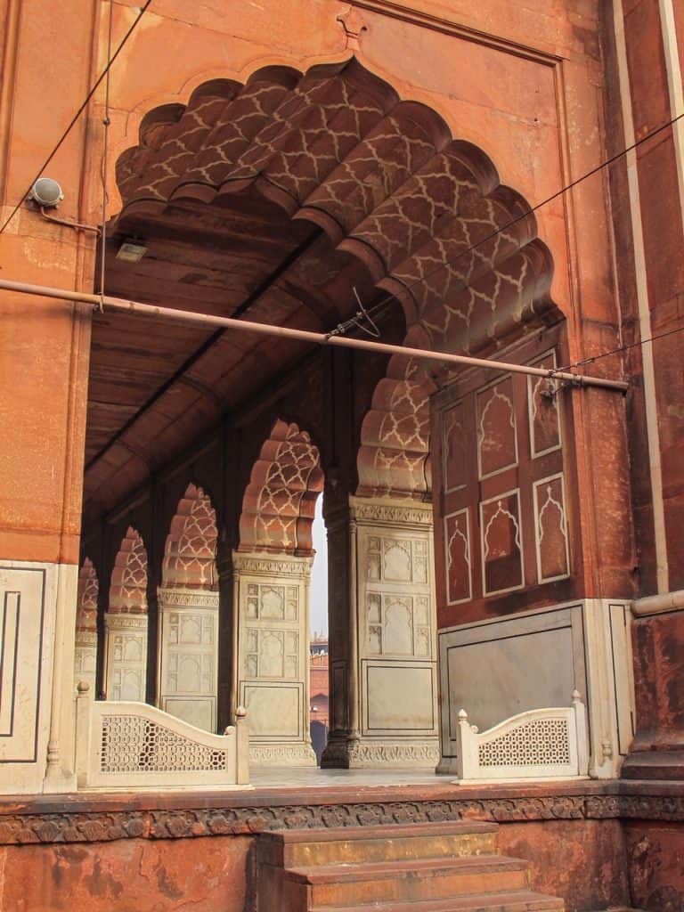A side view looking down the corridor with a series of arches and talented carvings on the red sandstone