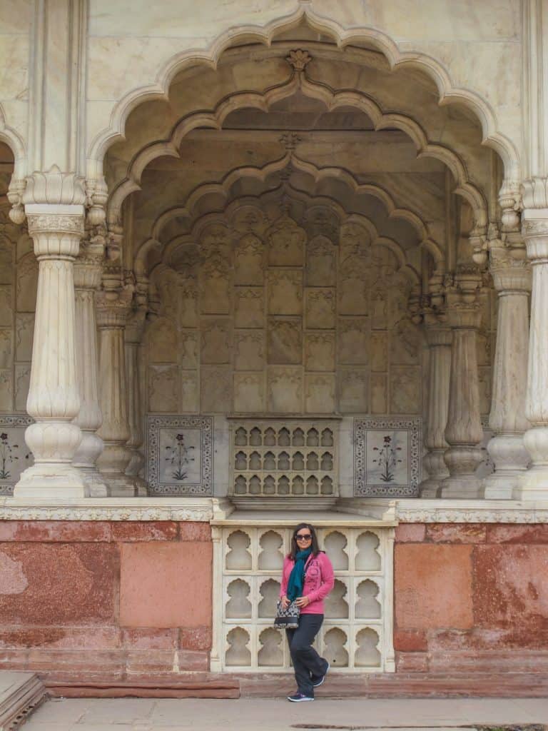 Me standing in front of a temple within the Red Fort dressed conservative in long pants and long sleeve top and scarf.
