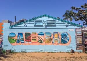 An art mural with a colorful painting that says Carlsbad in it with various scenes of life in Carlsbad in each letter