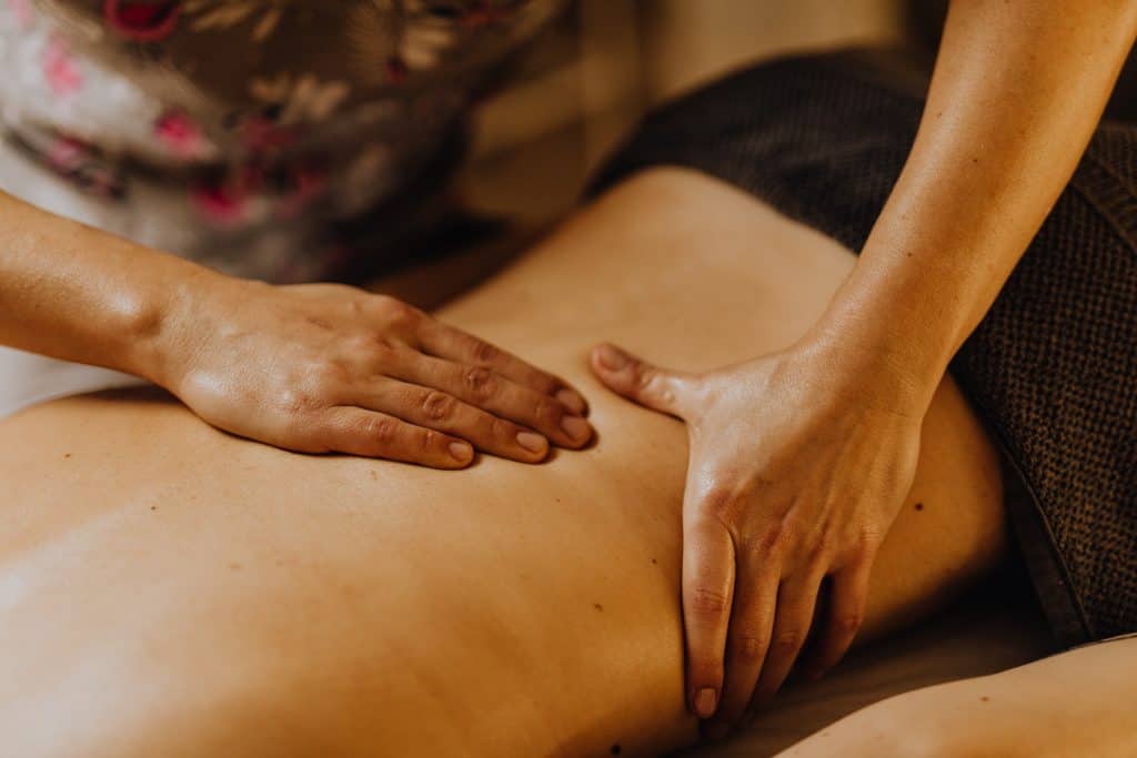 A woman on her stomach getting her back massaged at a spa