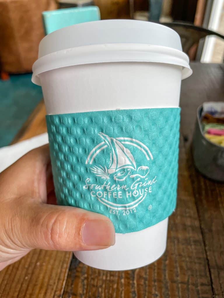 A close up view of my cup of coffee with the cute turquoise logo sleeve on my cup at The Southern Grind.