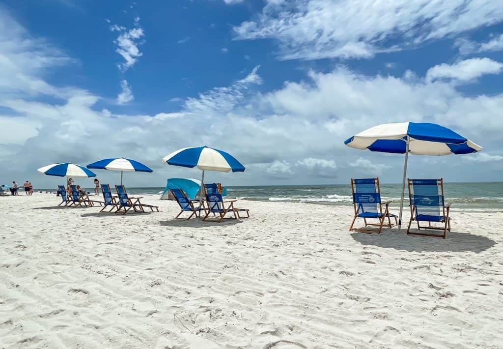 A row of blue and white lounge chairs on a sunny day on the white sand Orange Beach.