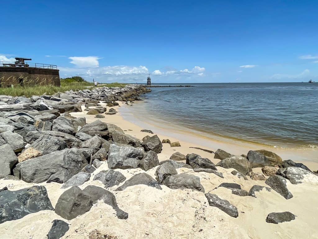 A small but idyllic beach with white sand and rocks bordering it on the East End of Dauphin Island.