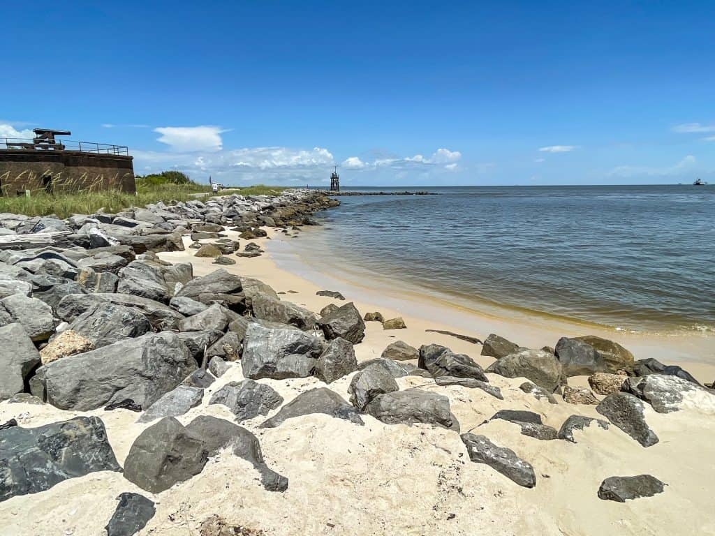 A small but idyllic beach with white sand and rocks bordering it on the East End of Dauphin Island.