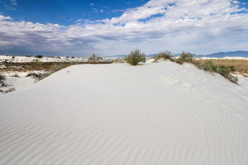 A white sand dune mound with ripples left behind by the wind.