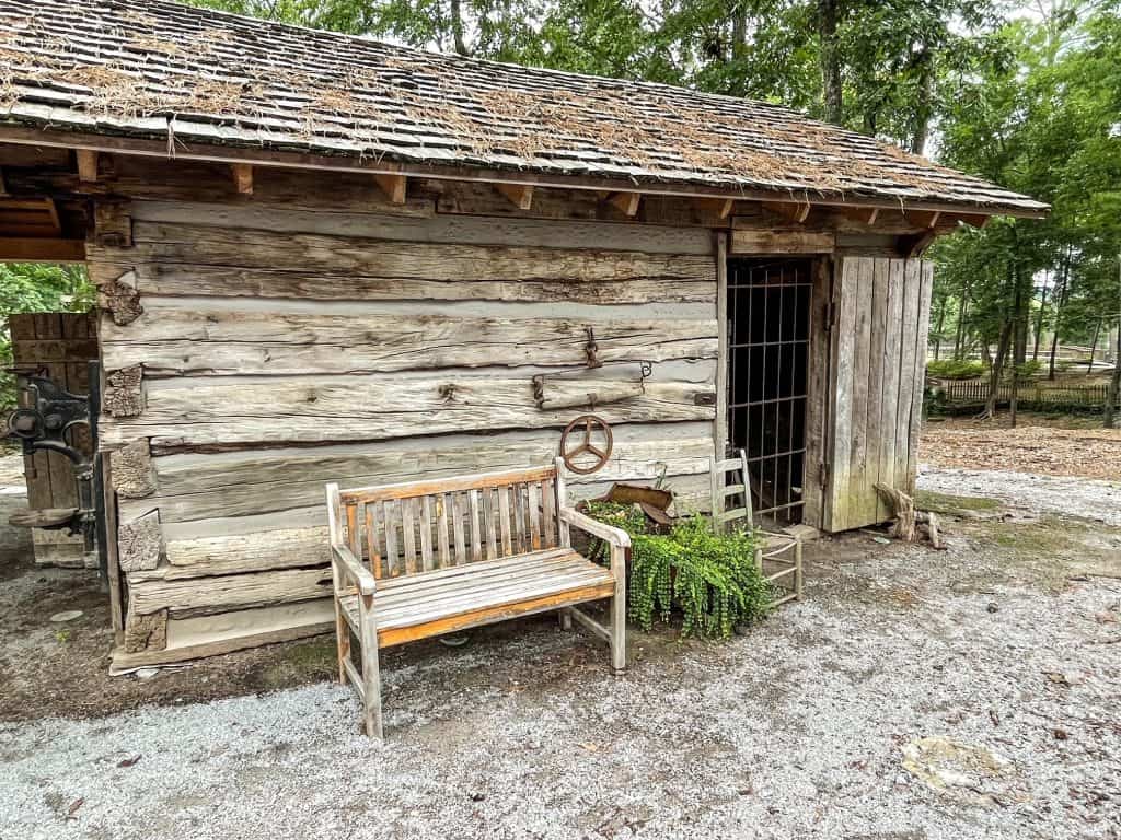 One of the wood cabins with a bench out front in the Pioneer Village portion of Noccalula Falls Park.
