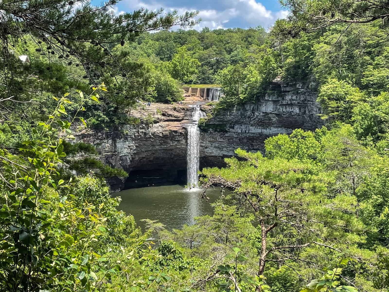 Looking across the canyon at DeSoto Falls waterfall in Alabama surround by lush forest and beautiful rock wall.