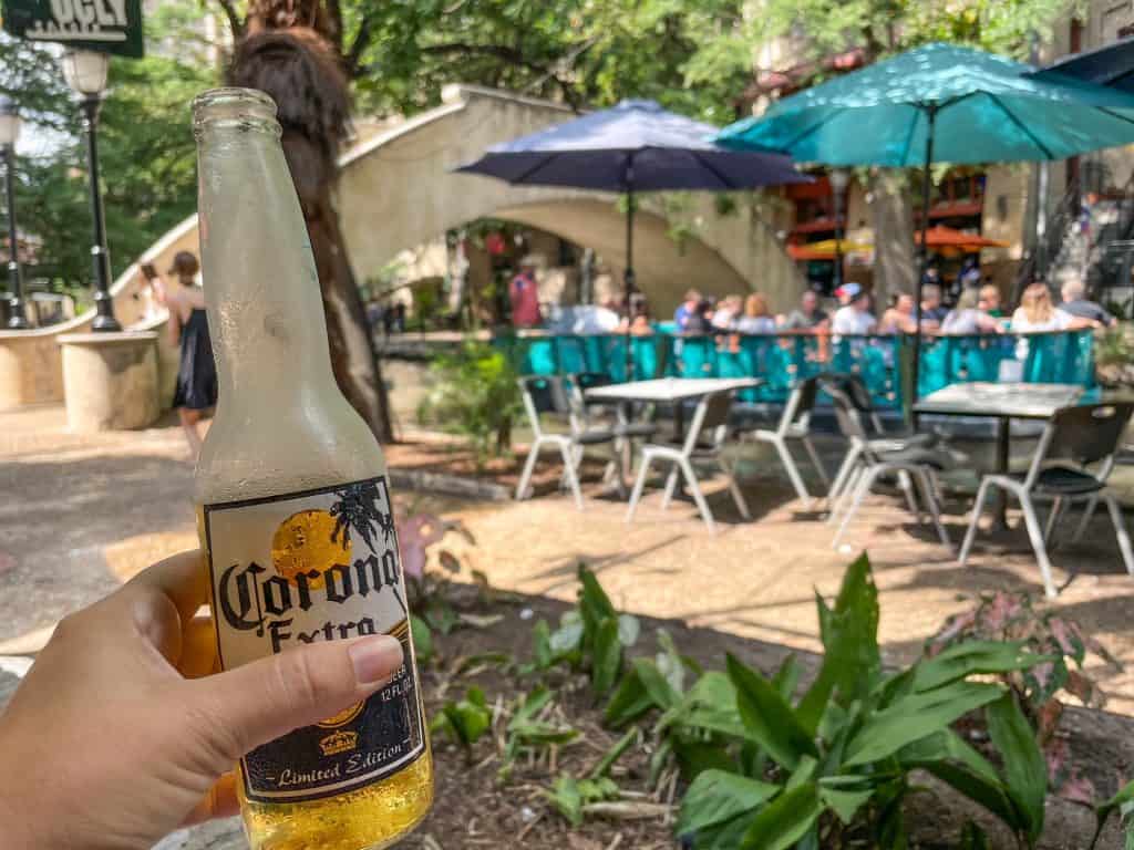 Drinking a beer while sitting at a restaurant on the River Walk in San Antonio watching people walk by and boats cruising in the distance.