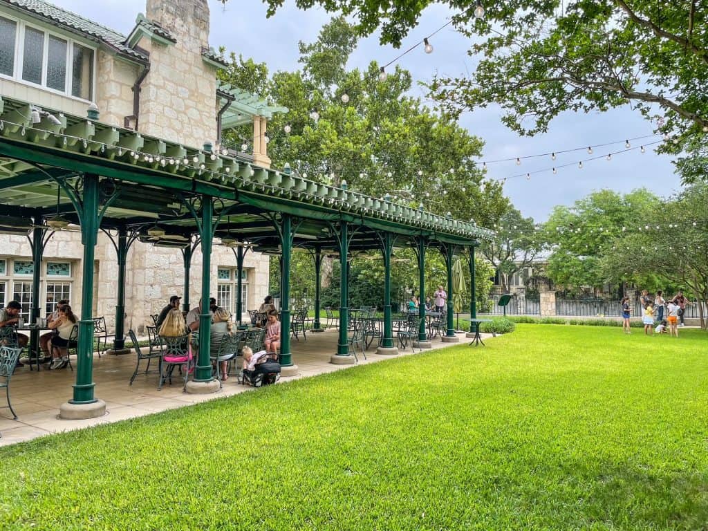 Outdoor dining under a veranda at Guenther House with a huge lawn in front of it and the river in the background.