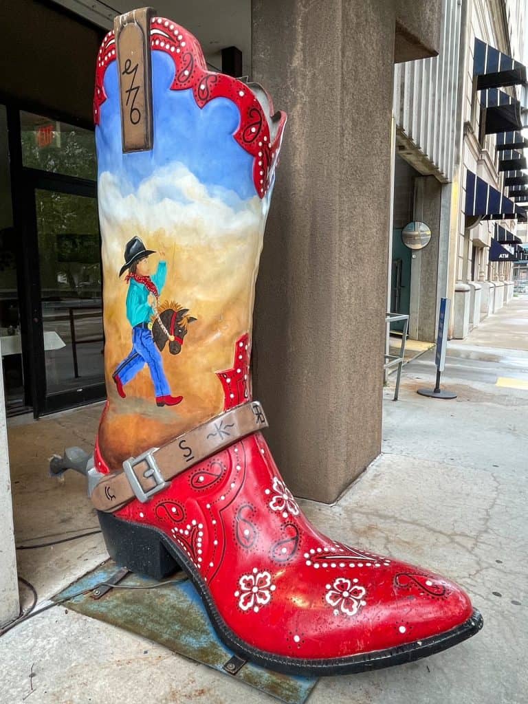 A huge cowboy boot painted in red and a western scene.
