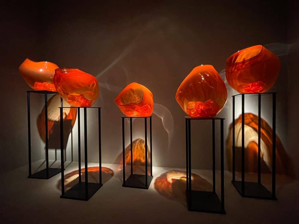 Orange glass sculptures on various pedestals.
