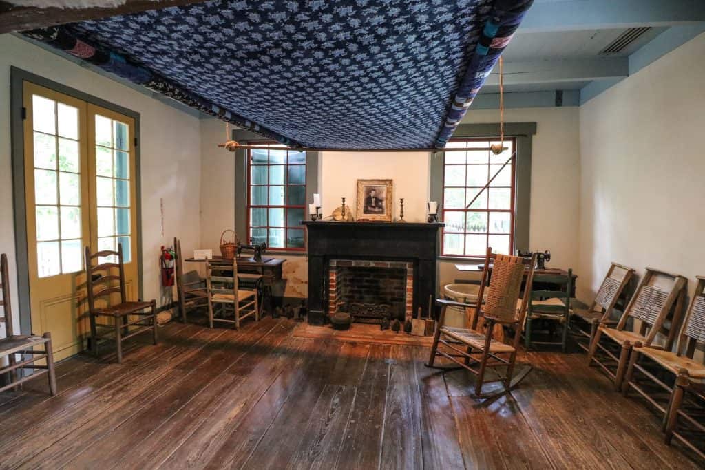 Inside of one of the homes with items that were previously used such as chairs fireplace and weaving.