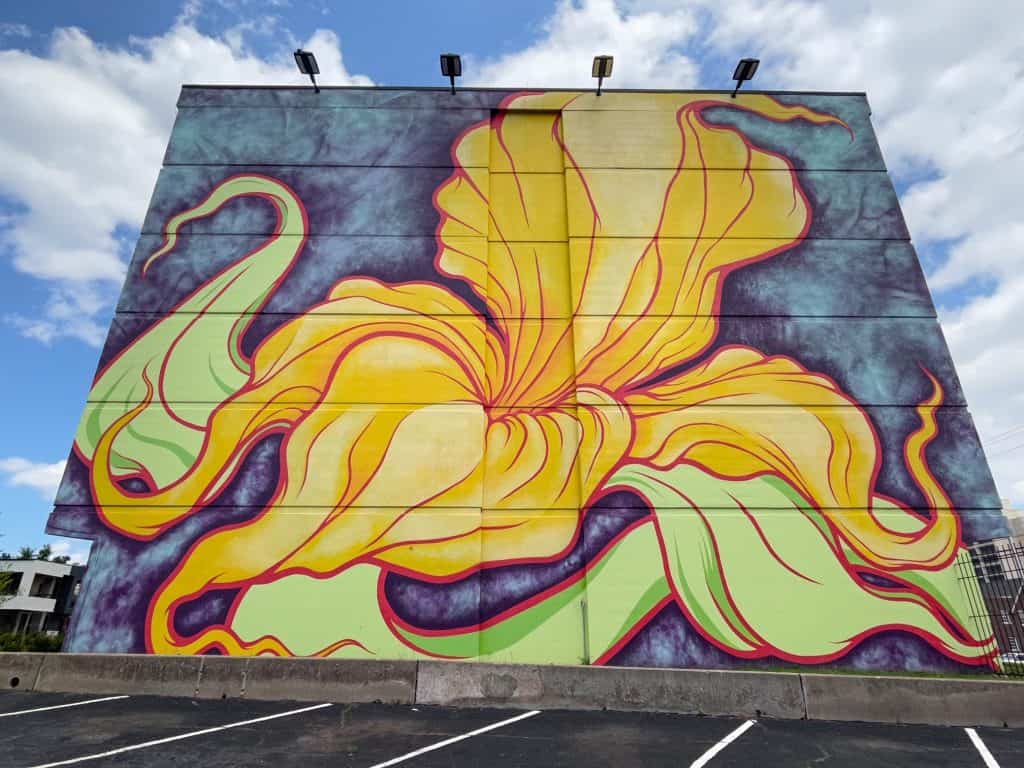 A huge beautiful yellow flower covering an entire side of a building outlined in shades of purple.