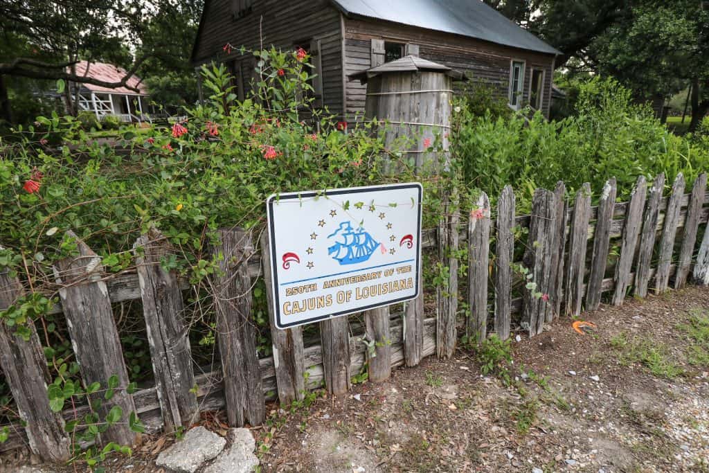 A wooden fence in at the front entrance to Acadia Village with a sign that says "Cajuns of Louisiana".