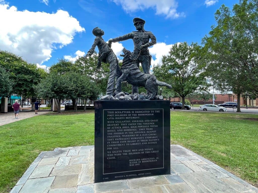 A statue showing a police officer mishandling a young African American boy and holding his angry dog to scare the boy.