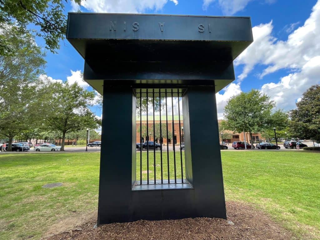 A statue that resembles a piece of a jail cell across from the previous photo where the children are not afraid.