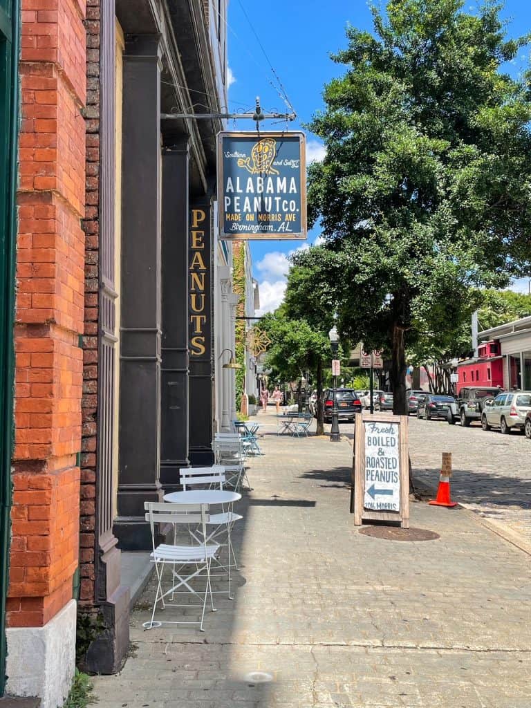 Standing on the sidewalk out side of the Alabama Peanut Co., with a sign that says peanuts and fresh boiled & roasted peanuts.