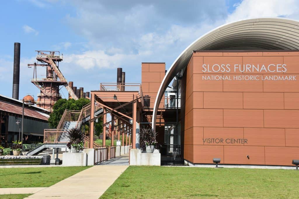 The Sloss Furnaces Visitor Center in rust color and green lawn out front.