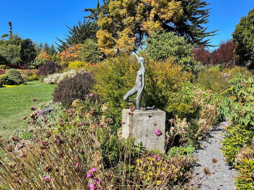 A statue of a woman among flowers and trees at the Mendocino Botanical Gardens.