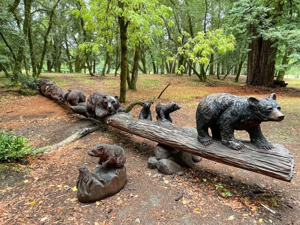 A series of bear carvings to look like they are crossing a log.