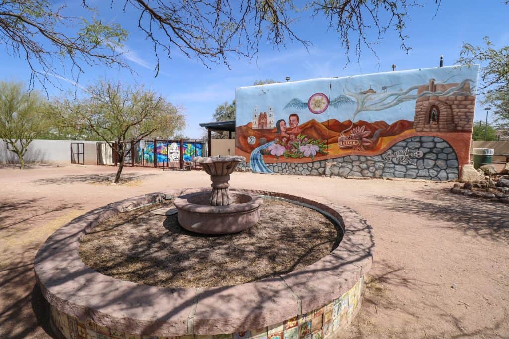 A beautiful courtyard with art murals, an empty fountain and trees in Barrio Viejo area of Tucson.