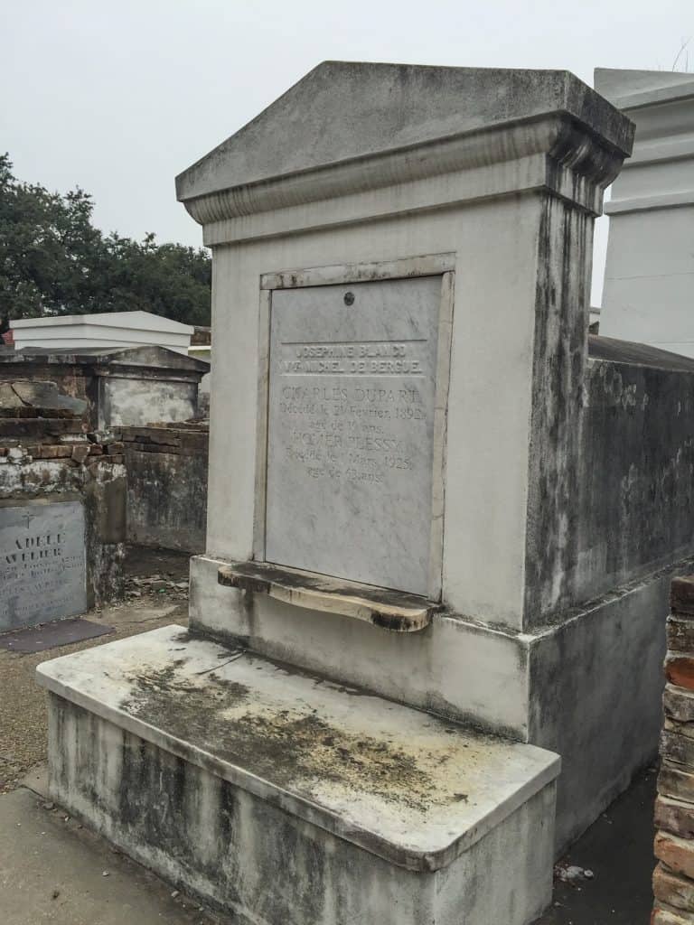 A very old and tall tomb made of marble and concrete in a cemetery in NOLA.
