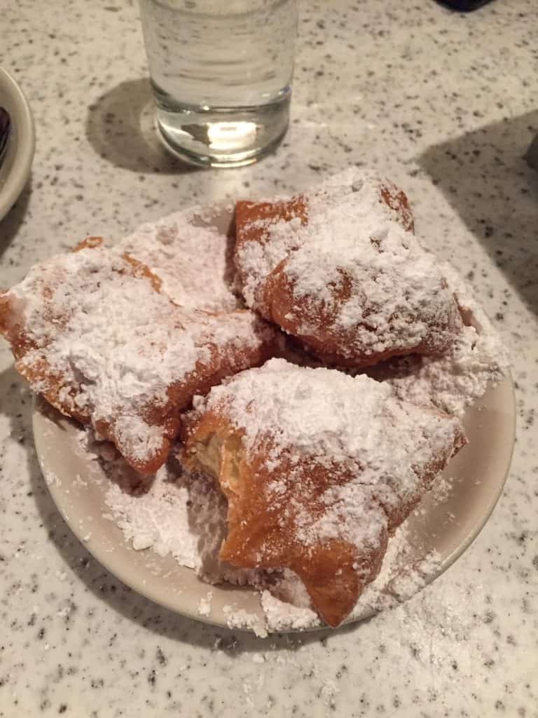 A plate of 3 beignets covered in powder sugar from Cafe du Monde.