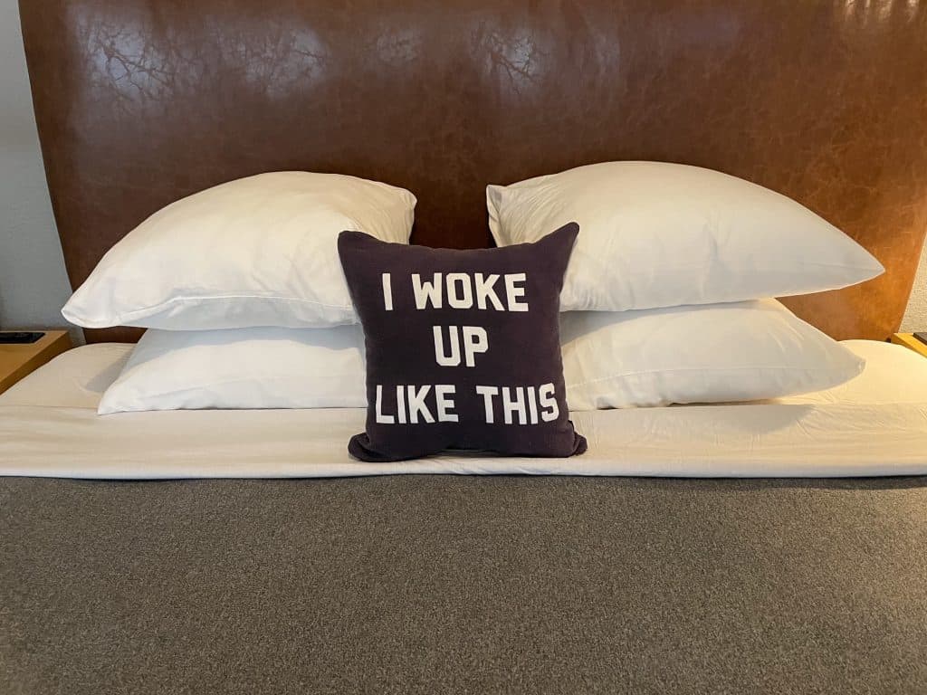 A cute small pillow that says "I woke up like this" on a bed in a hotel in New Orleans.