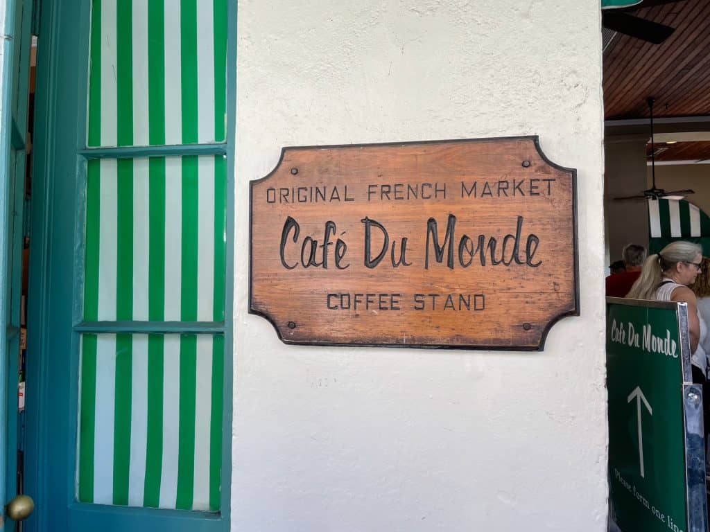 A wooden sign on the building for Cafe du Monde as the original French market coffee stand.